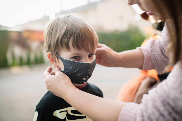 Mother Putting Protective Face Mask On Child