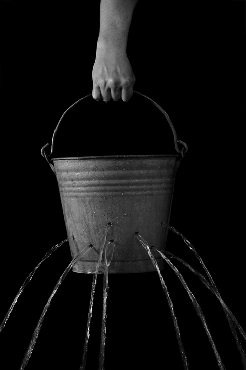 Water Bucket With Holes Loosing Water, Held By A Hand