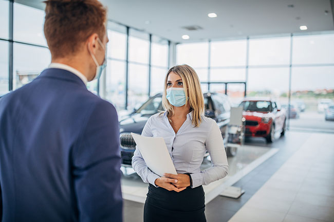 Two people wearing masks at auto dealership