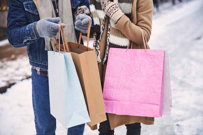 Two people standing closely holding shopping bags.