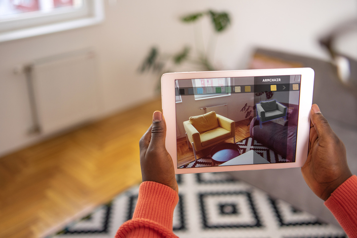 A consumer using augmented reality to test a seating set up in their home using a tablet.  