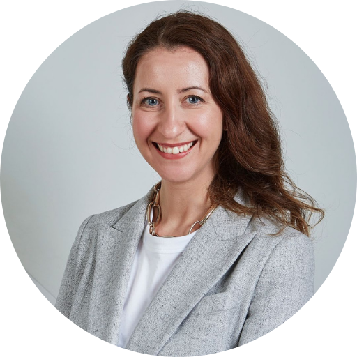 Ester Marchetti’s headshot. Marchetti smiling at camera on a gray background.