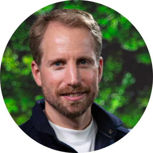 Dani Kamras’ headshot with greenery in the background.