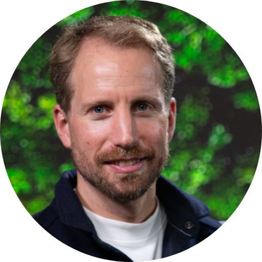 Dani Kamras’ headshot on a background of greenery.