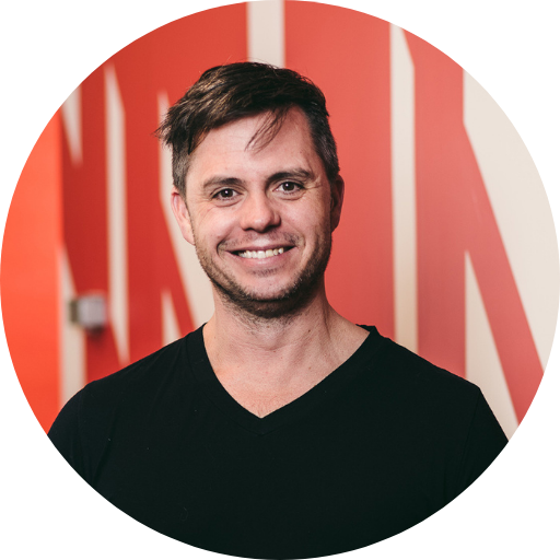 Andrew Reid’s circular headshot on a red background.